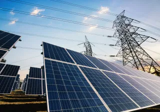 A photo of solar panels with power lines in the background.
